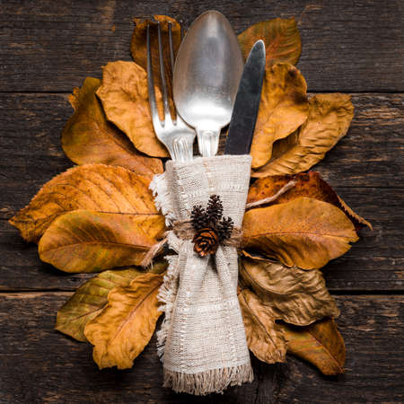 Thanksgiving Meal Setting. Seasonal table setting. Thanksgiving autumn place setting with cutlery and arrangement of colorful fall leaves.の写真素材