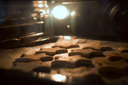 Christmas cookies baking in the oven. Christmas baking. Gingerbread biscuits on baking tray.の写真素材