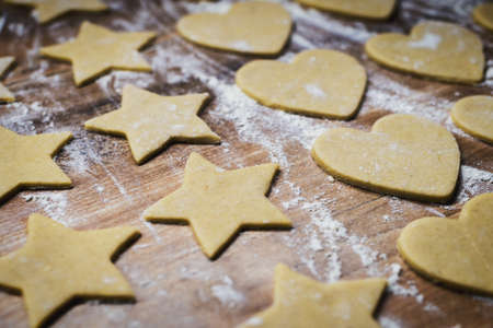 Christmas baking. Making gingerbread biscuits. Cookie dough in heart and star shape on kitchen...