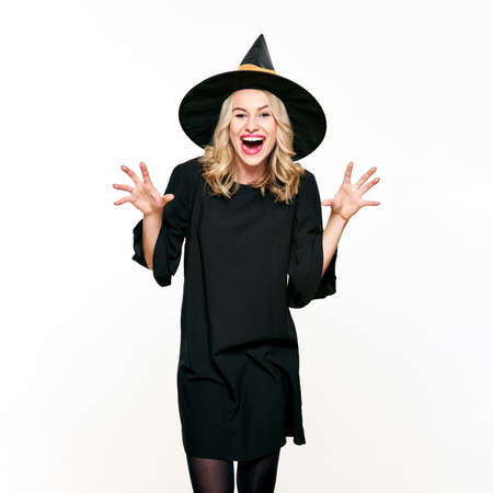 Attractive young woman dressed in witch halloween costume isolated over white background. Sensual...