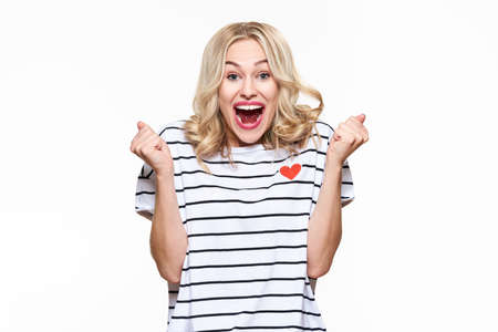 Excitement and amazement. Attractive young woman clenching fists, screaming with joy, with eyes full...