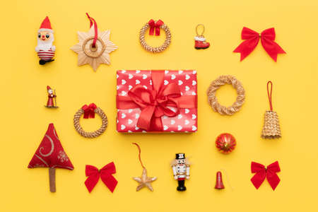 Red christmas gift and many retro christmas ornaments isolated on bright yellow background. Christmas composition.の写真素材