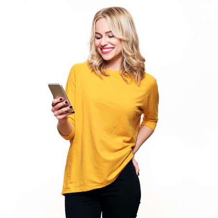 Gorgeous smiling woman looking at her mobile phone. Woman texting on her phone, isolated over white...