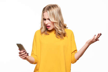 Shocked angry young woman looking at her mobile phone in disbelief. Woman staring at shocking text...