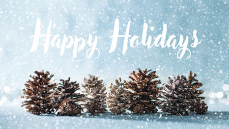 Beautiful Christmas Background. Pine cones on shiny blue background and falling snow with defocused christmas lights in the background.の写真素材
