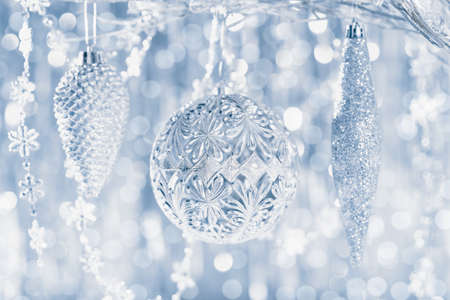 Shiny silver christmas ornaments hanging on a tree, with defocused christmas lights in the background.の写真素材
