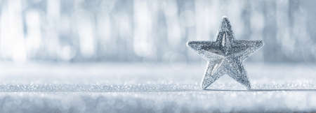 Shiny silver christmas star with defocused christmas lights in the background. Christmas banner with copy space.の写真素材