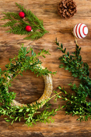 Boxwood Christmas wreath. DIY Christmas decoration concept. Wooden desk top view.