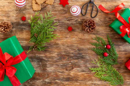 DIY Gift Wrapping. Beautiful green christmas gifts with red bow on rustic wooden table. Top view of...