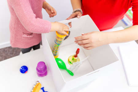 Toddler girl in child occupational therapy session doing sensory playful exercises with her therapist.の写真素材