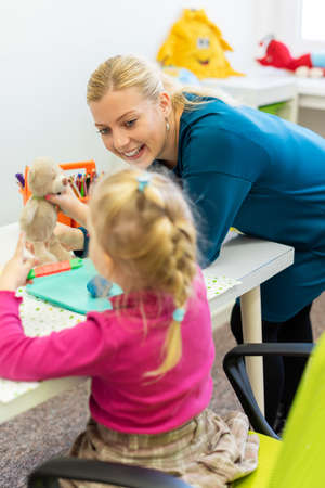 Toddler girl in child occupational therapy session doing sensory playful exercises with her therapist.の写真素材