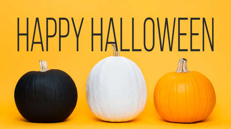 Three large Halloween pumpkins side by side over orange background. Halloween greeting card.の写真素材