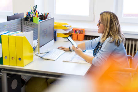 Female child therapist in an office during a phone call, using online calendar to schedule patients...