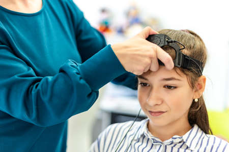 Young teenage girl and child therapist during EEG neurofeedback session. Electroencephalography concept.の写真素材