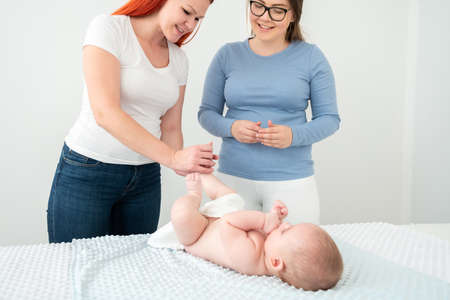 Female massage therapist teaching young mother how to massage her newborn baby boy. Baby massage concept.の写真素材