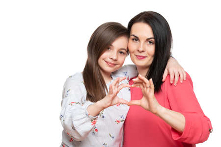 Cute girl and her mother making together heart shape hand gesture. Family love, care and support....