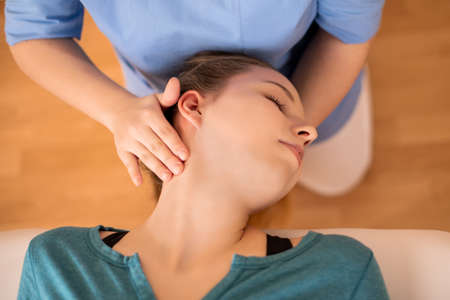 Female physiotherapist or a chiropractor adjusting patients neck. Physiotherapy, rehabilitation...