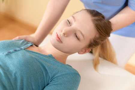 Female physiotherapist or a chiropractor adjusting patients neck. Physiotherapy, rehabilitation...