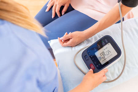 Young woman having her blood pressure checked by a nurse, doctor or a health visitor. Heart health....