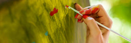 Female artist working on an art canvas painting outdoors in her garden. Mindfulness, art therapy, creativity and creative hobbies concept banner.の写真素材