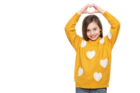 Studio portrait of a little girl on white background making a heart gesture with her hands. Fostering a child, humanitarian aid, cooperation, donation and support concept.の写真素材