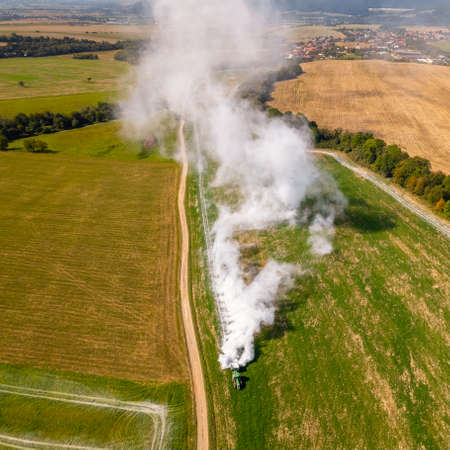 Aerial view of a tractor spreading lime on agricultural fields to improve soil quality after the autumn harvest. The use of lime powder to neutralize the acidity of the soil.の写真素材