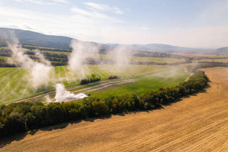 Aerial view of a tractor spreading lime on agricultural fields to improve soil quality after the autumn harvest. The use of lime powder to neutralize the acidity of the soil.の写真素材