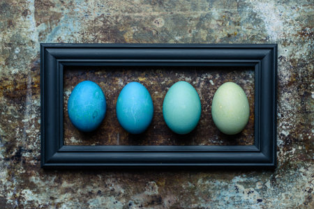 Happy Easter rustic background. DIY dyed various shades of blue Easter eggs and wooden picture frame...