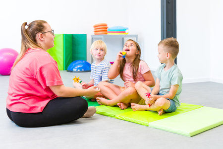 Group of young children making breathing exercises during physical therapy session. Kids in group...