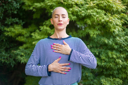 Young female cancer patient meditating doing breathing exercises in her garden. Mental health, life balance, mindfulness and meditation concept.の写真素材