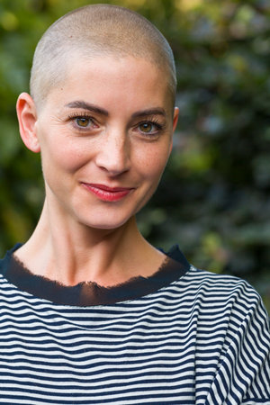 Beautiful young positive female cancer survivor smiling outdoors portrait.