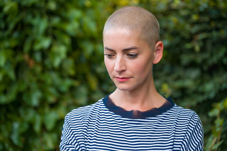 Young female cancer patient garden portrait. Mental health, emotional support, struggles and coping mechanisms during cancer illness.の写真素材