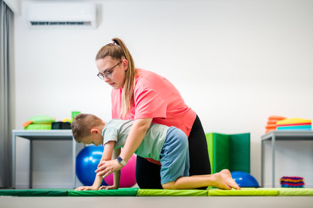 Young boy exercising with physical therapist during therapy session. Child physical therapy. Bilateral coordination.の写真素材