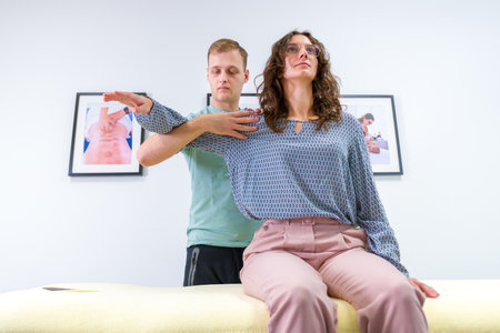Woman with shoulder pain in physical therapy. Chiropractor examining patients injured shoulder joint.の写真素材