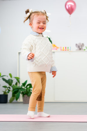 Full body portrait of a cute 4 year old girl with Down Syndrome, standing in her room, looking at camera smiling.の写真素材