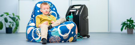 Oxygen therapy, also referred to as supplemental oxygen. Young boy with respiratory problems inhaling oxygen through nasal cannula attached to concentrator machine.の写真素材