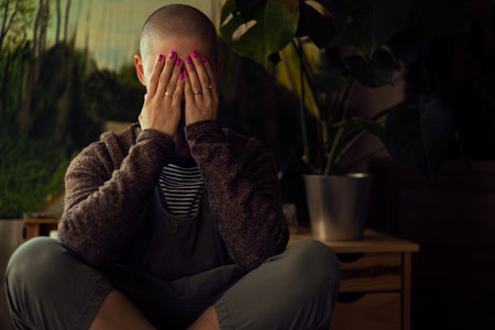 Cancer patient with head in hands indoors portrait. Health insurance, medical expenses, loss of income. Mental health, wellbeing, life balance during illness.の写真素材