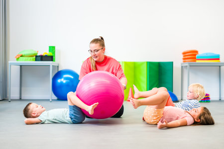 Kids group physical therapy. Children and female physical therapist exercising during session. Bilateral coordination or integration.の写真素材