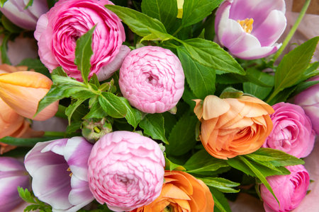 Spring bouquet. Beautiful pastel colored fresh flowers arrangement. Birthday bouquet made of tulips and ranunculus photographed outdoors.の写真素材