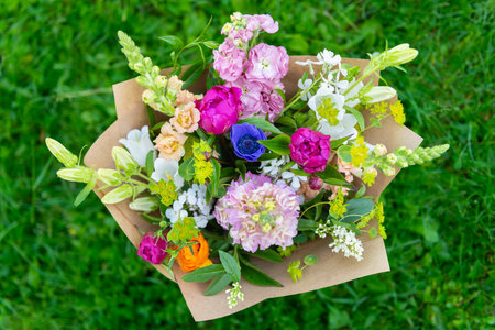 Wrapped flower bouquet made of mixed spring flowers. Beautiful vibrant colored fresh flowers arrangement. Birthday bouquet with snapdragons, peonies and matthiola stock.の写真素材