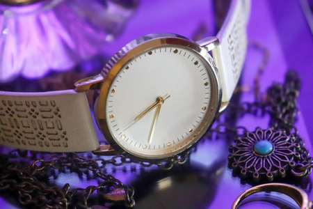 white clock with jewelry in a purple backgroundの写真素材