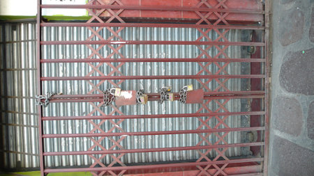 old metal door is locked with three padlocks with a rusty chainの写真素材