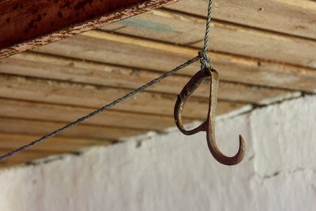 Old rusty meat hook hanging on a rope
