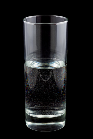 Half full glass of water isolated on blackの写真素材