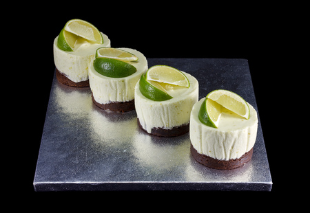Four small cakes decorated with lime wedges isolated on blackの写真素材