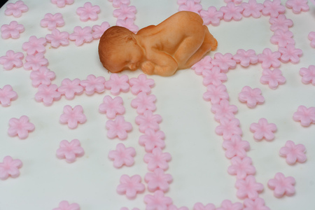 One white cake decorated with a newborn baby and pink flowers isolated on blackの写真素材