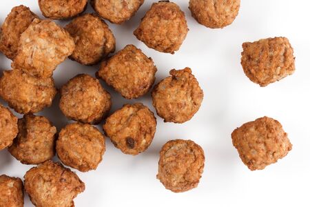 Close-up of lots of meatballs from above on a white background