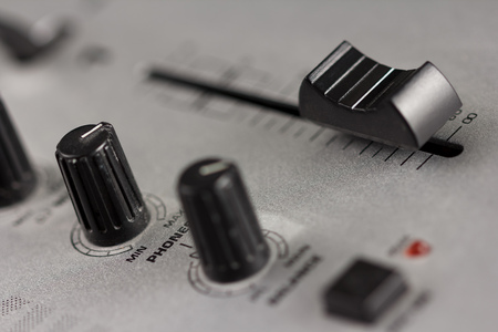 Two knobs and a fader of a DJ mixer with metal surface