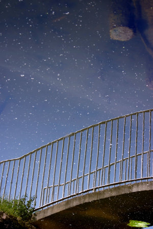 Pedestrian bridge reflecting in water looking like starry night sky.の写真素材
