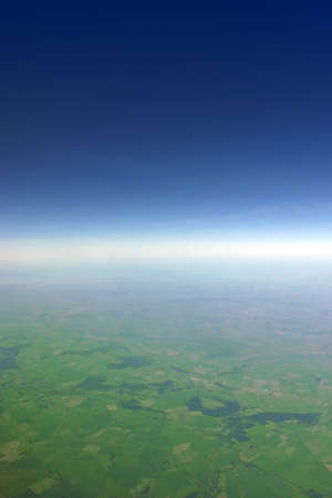 Aerial view of green fields fading away at the horizon line